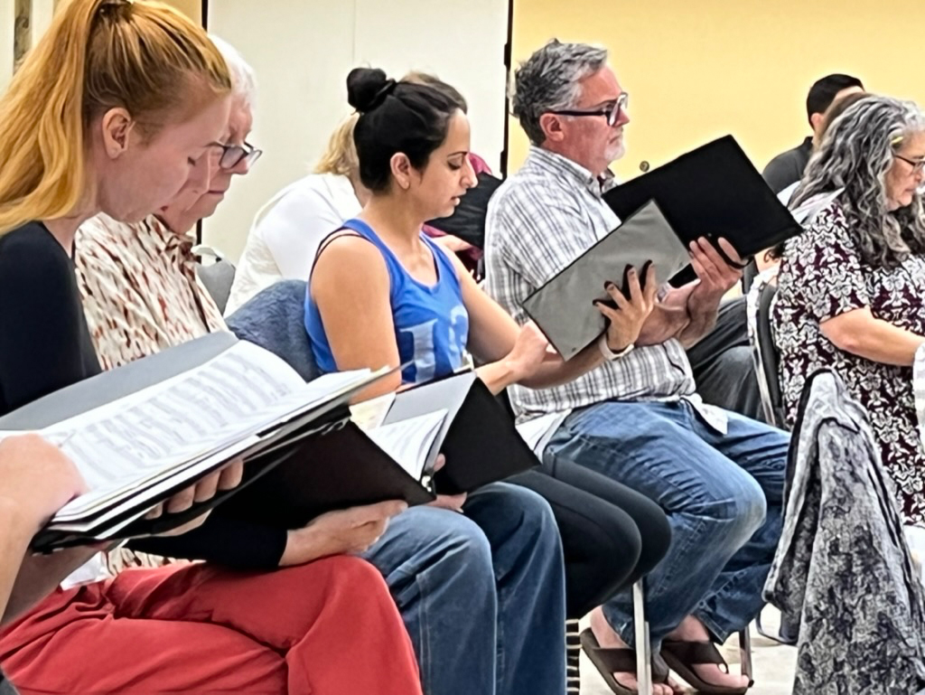 Singers sitting down and rehearsing their music.